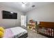 This bedroom includes a bed, TV and a dollhouse near the crib at 13657 W Paso Trl, Peoria, AZ 85383