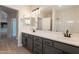 Bathroom featuring a large mirror, double sinks with dark cabinetry, and natural light at 14771 W Columbus Ave, Goodyear, AZ 85395