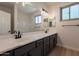 Bathroom featuring a large mirror, double sinks with dark cabinetry, and natural light at 14771 W Columbus Ave, Goodyear, AZ 85395