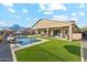 Inviting backyard featuring a pool, fire pit, covered patio, and lush artificial grass, perfect for outdoor entertaining at 16417 W Fawn Dr, Goodyear, AZ 85338