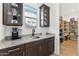 Butler pantry with granite countertop, glass cabinets, a sink, and open access to the walk-in pantry at 16417 W Fawn Dr, Goodyear, AZ 85338