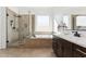 Bathroom featuring a glass-door shower, soaking tub, and sleek dark cabinetry at 16417 W Fawn Dr, Goodyear, AZ 85338