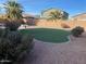Landscaped backyard with artificial turf, stone accents, and privacy wall at 17344 W Adams St, Goodyear, AZ 85338
