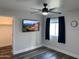 Modern bedroom with mounted television, ceiling fan, and dark wood-look flooring offers a comfortable and stylish retreat at 17344 W Adams St, Goodyear, AZ 85338