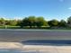 Scenic view of a neighborhood green space with mature trees and a walking path under a sunny sky at 17344 W Adams St, Goodyear, AZ 85338