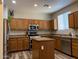 Well-lit kitchen boasts stainless steel appliances, an island, and wooden cabinets, offering ample storage and workspace at 17344 W Adams St, Goodyear, AZ 85338