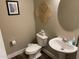 A quaint powder room with a pedestal sink and decorative wall art offers a stylish and functional space at 17344 W Adams St, Goodyear, AZ 85338