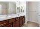 Bathroom vanity with dual sinks, large mirror and wood cabinets at 18041 W Ivy Ln, Surprise, AZ 85388