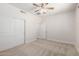 Well-lit bedroom showcasing a ceiling fan, closet with sliding doors, and neutral carpeting for a comfortable living space at 18041 W Ivy Ln, Surprise, AZ 85388