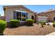 Single-story home with stone accents, shutters, and a low-maintenance gravel front yard with trimmed bushes at 18041 W Ivy Ln, Surprise, AZ 85388