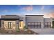 Modern home featuring a two-car garage with glass door, stone accents and desert landscaping at dusk at 24651 N 127Th Way # 30, Scottsdale, AZ 85255