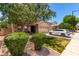 Landscaped front yard with manicured lawn, trees, and a modern white car in the driveway at 283 W Tahiti Dr, Casa Grande, AZ 85122