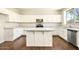Well-lit kitchen with white cabinets, stainless steel appliances, and spacious island on dark hardwood floors at 2880 E Nunneley Rd, Gilbert, AZ 85296