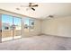 A large carpeted living room is naturally lit through windows and a sliding glass door to the outside at 2880 E Nunneley Rd, Gilbert, AZ 85296