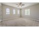 Sunlit bedroom with plush carpet, ceiling fan, and unique windows offering ample natural light at 3310 E Los Gatos Dr, Phoenix, AZ 85050