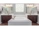 A bathroom boasts double sinks, a white soaking tub, and rich brown cabinetry at 3715 W Teresa Dr, New River, AZ 85087