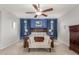 A primary bedroom features a ceiling fan, a wooden bed frame, and blue accent wall with white trim windows at 3715 W Teresa Dr, New River, AZ 85087