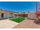 Spacious backyard with synthetic grass, gravel, and a covered patio at 39 N Maple St, Mesa, AZ 85205