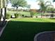 Beautifully manicured backyard with lush green grass, mature trees, and a wrought iron fence at 4083 E Rustler Way, Gilbert, AZ 85297