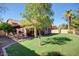 Serene backyard with lush green grass, patio seating, and a shade tree at 4083 E Rustler Way, Gilbert, AZ 85297