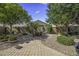 Charming backyard featuring a paved patio, lush landscaping, trees, and desert plants at 43330 W Delia Blvd, Maricopa, AZ 85138