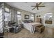 Spacious bedroom features wood floors, a ceiling fan, and seating area with an armchair at 43330 W Delia Blvd, Maricopa, AZ 85138