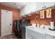 Modern laundry room with side-by-side gray washer and dryer, white countertops and cabinetry, and a gold faucet at 4727 E Rancho Caliente Dr, Cave Creek, AZ 85331
