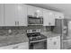 Modern kitchen with sleek white cabinets, granite countertops, modern backsplash, and stainless steel appliances at 4732 S 38Th Gln, Phoenix, AZ 85041