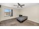 Simple bedroom with tan walls and carpet, a gray bed set, a window, and a ceiling fan at 5401 N 104Th Dr, Glendale, AZ 85307