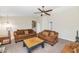 Comfortable living room featuring matching brown sofas, neutral paint, a ceiling fan, and adjacent white walls at 5401 N 104Th Dr, Glendale, AZ 85307