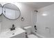 Modern bathroom featuring a sleek round mirror, white vanity, and shower-tub combo at 733 W El Prado Rd, Chandler, AZ 85225