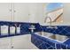 Charming kitchen features a blue tiled sink and countertops, complemented by white cabinets and a bright, sunny window at 917 W Willetta St, Phoenix, AZ 85007