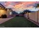 Evening backyard with artificial turf, patio, BBQ grill, and decorative overhead string lights at 9831 E Tupelo Ave, Mesa, AZ 85212