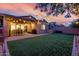 Backyard at twilight features a covered patio, outdoor seating, and artificial turf at 9831 E Tupelo Ave, Mesa, AZ 85212