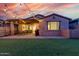 Backyard at twilight with patio, lawn and string lights for outdoor entertaining at 9831 E Tupelo Ave, Mesa, AZ 85212