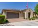Charming single-story home featuring an arched entryway, desert landscaping, an American flag, a tile roof, and a two car garage at 10310 E Tillman Ave, Mesa, AZ 85212
