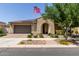 Charming single-story home featuring an arched entryway, desert landscaping, an American flag, and a two car garage at 10310 E Tillman Ave, Mesa, AZ 85212