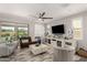Open-concept living room featuring neutral tones, stylish furniture, and large windows with access to the backyard at 10310 E Tillman Ave, Mesa, AZ 85212