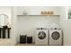 Well-lit laundry room with modern appliances, storage baskets and floating shelves at 11940 W Calle De Pompas --, Peoria, AZ 85383