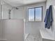 Modern bathroom featuring a glass-enclosed shower, pebble flooring, and white tile surround at 12706 W Pasaro Dr, Peoria, AZ 85383