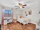 Cozy bedroom with a plush chair, bed with decorative pillows, and a dedicated desk area, illuminated by a modern fan at 12706 W Pasaro Dr, Peoria, AZ 85383