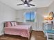 Bright bedroom with a pink bed, decorative lights, ceiling fan, and a window that offers a pleasant view at 12706 W Pasaro Dr, Peoria, AZ 85383