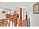 A home hallway featuring hardwood floors, an elegant wooden stair railing, and a glimpse into the cozy living room area at 12706 W Pasaro Dr, Peoria, AZ 85383