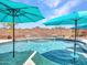 Sparkling swimming pool with water feature surrounded by brick walls and sun umbrellas at 12706 W Pasaro Dr, Peoria, AZ 85383