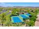 Aerial view of well-maintained community tennis courts surrounded by lush landscaping and palm trees at 12706 W Pasaro Dr, Peoria, AZ 85383