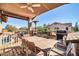 Inviting covered deck with a wooden table, ceiling fan, heater, BBQ grill, and view of the pool and trampoline at 13051 N 75Th Dr, Peoria, AZ 85381