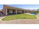 Expansive backyard with a covered patio, green lawn, mature landscaping, and a serene pool area at 14538 W Sheridan St, Goodyear, AZ 85395