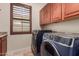 Well-organized laundry room with modern machines, window, and cabinets at 14538 W Sheridan St, Goodyear, AZ 85395