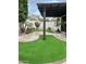 Expansive backyard with lush artificial grass, a stone paver patio, mature trees, and manicured landscaping at 20962 W Thomas Rd, Buckeye, AZ 85396