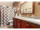 Bathroom featuring wooden cabinets, granite countertops, framed mirror, and a shower with a patterned curtain at 20962 W Thomas Rd, Buckeye, AZ 85396